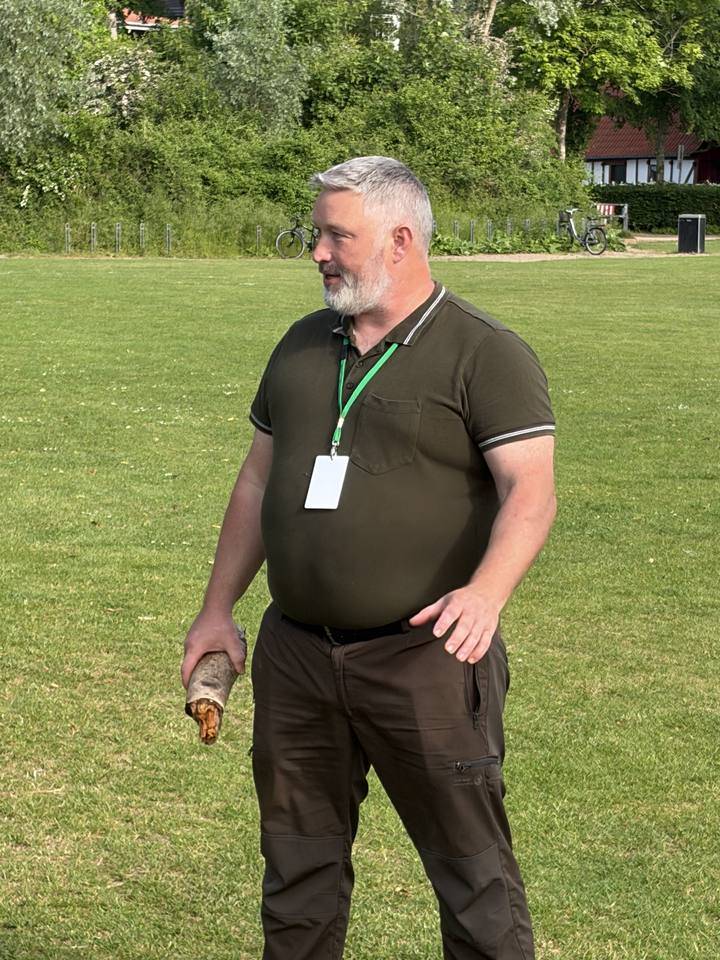 Kristian G. G. Dansted står udendørs på en græsplæne med træer bagved